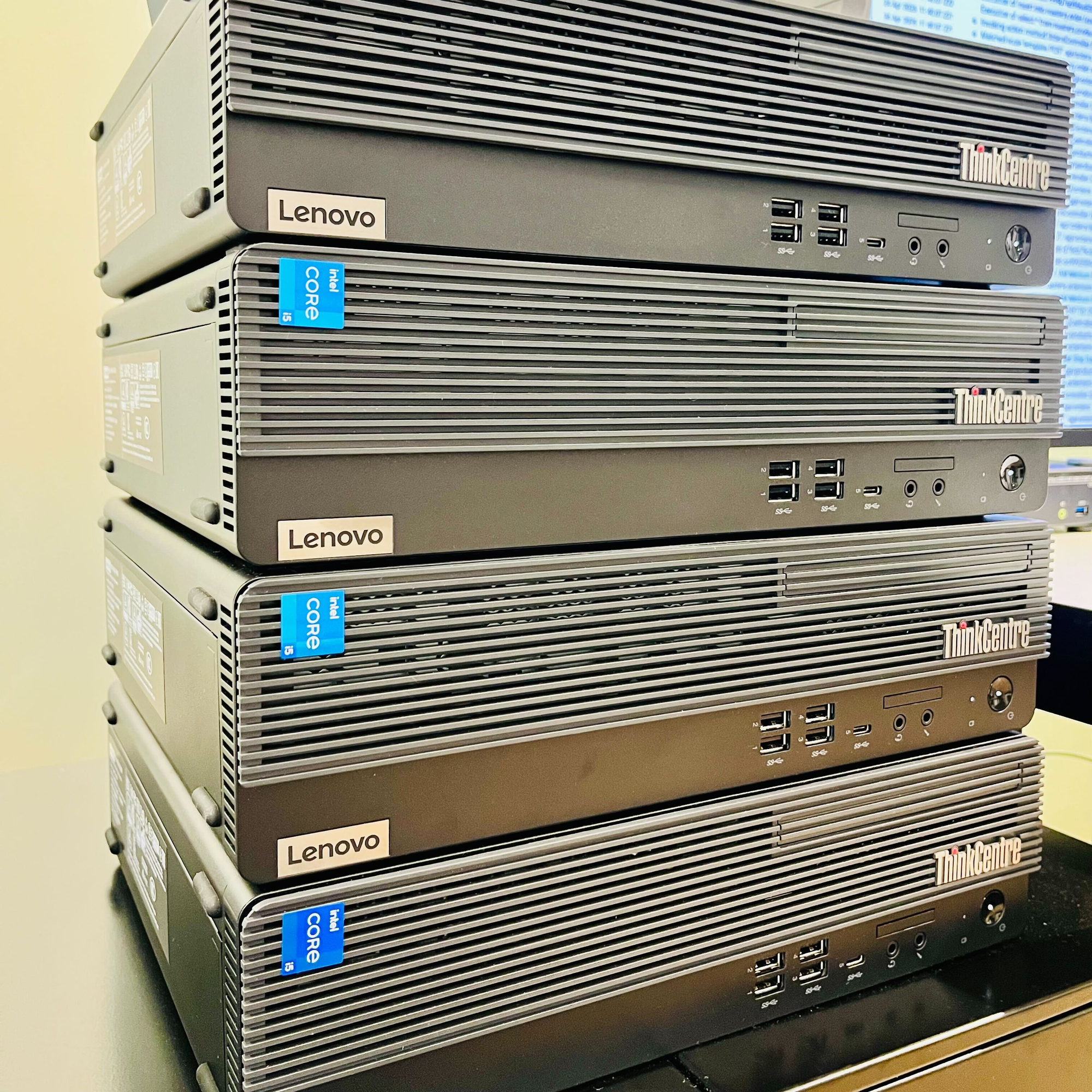 Four small-form-factor Lenovo ThinkCentre machines stacked vertically.